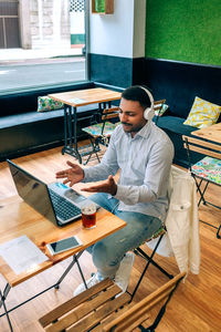 Side view of man using laptop while sitting on table