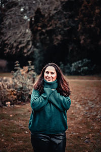 Portrait of a smiling young woman standing on field