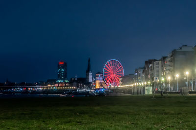 Illuminated amusement park against sky at night