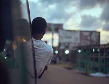 Rear view of man standing on street against sky