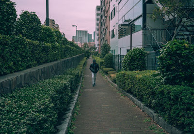 Man walking on footpath amidst buildings in city