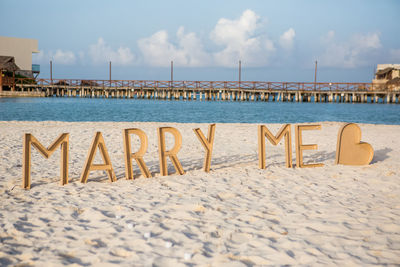 Marry me message at sandy beach against sky