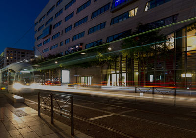 Light trails on street amidst buildings in city at night