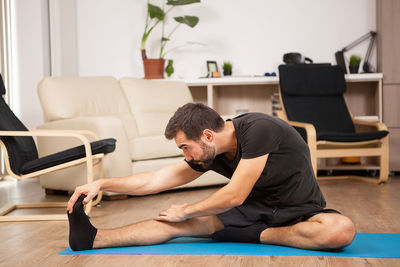 Side view of woman sitting on sofa at home