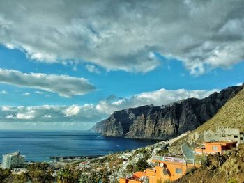 View of town by sea against cloudy sky