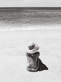 Midsection of woman wearing hat while standing on beach
