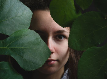 Portrait of young woman with green leaves