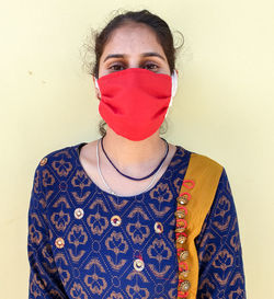 Portrait of young woman standing against wall