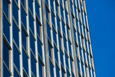 Low angle view of glass building against clear blue sky