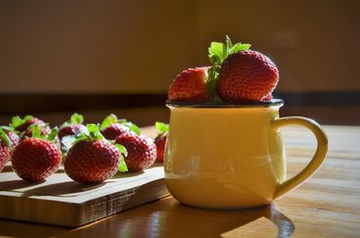 Close-up of strawberry fruits and cup on table