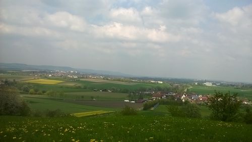 Scenic view of grassy field against cloudy sky