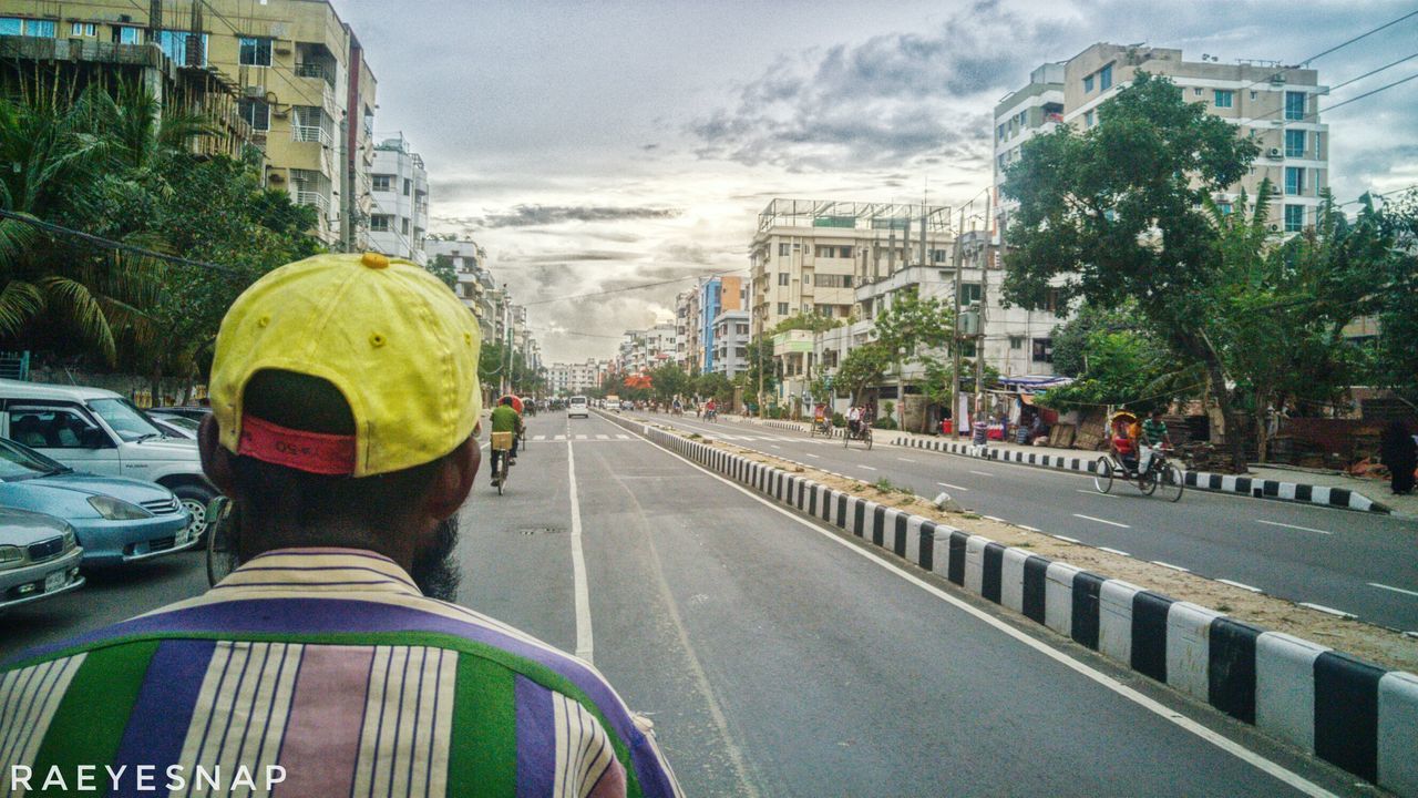 real people, road, building exterior, built structure, architecture, men, land vehicle, street, rear view, mode of transport, transportation, day, city, car, large group of people, outdoors, sky, lifestyles, tree, adult, people