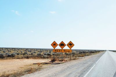 Animal crossing signs by road against sky