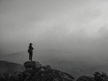 Man standing on rock against sky