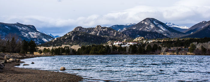 Scenic view of lake by snowcapped mountains against sky