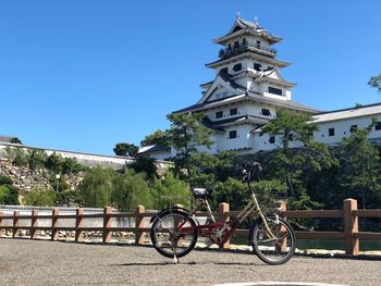 Bicycle parked by building against clear blue sky