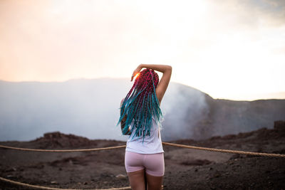 Rear view of woman looking at mountains against sky