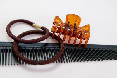 Close-up of comb with hair clip and rubber bands on white background