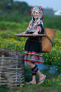 Full length of woman holding basket while standing on field