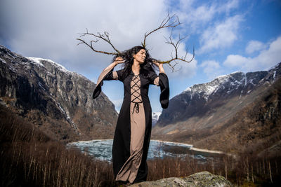 Young woman standing on mountain against sky