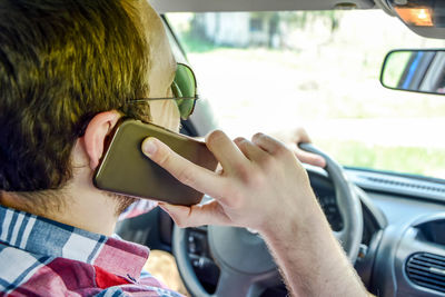 Close-up of man talking on mobile phone while driving car