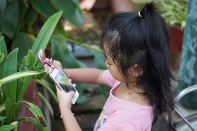 Close-up of girl taking picture of plants