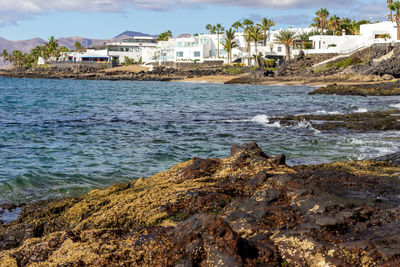 Scenic view of sea by buildings against sky