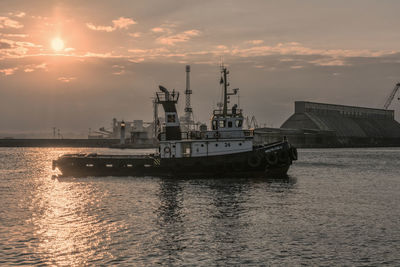 Ship at harbor against sky during sunset