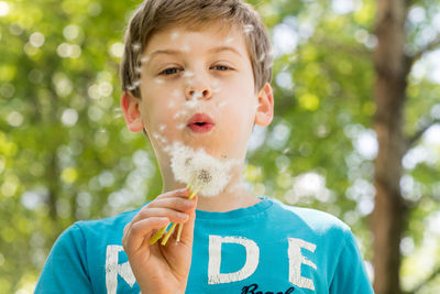 Portrait of boy blowing dandelion