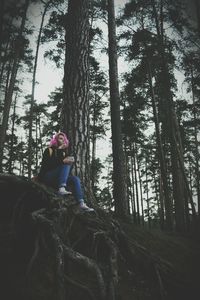 Woman amidst trees in forest against sky