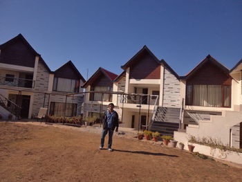 Rear view of boy walking on houses against sky