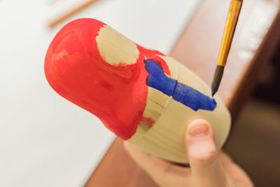 Kid decorating wooden doll toy russian matrioshka at the workshop