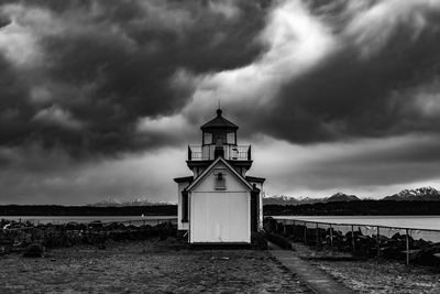 Lighthouse amidst sea and buildings against sky