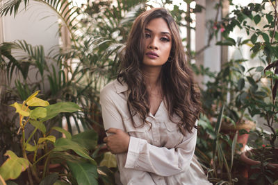 Portrait of beautiful young woman standing against plants