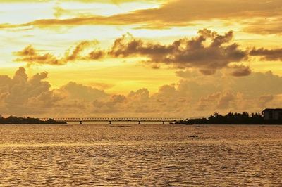 Scenic view of sea against cloudy sky at sunset