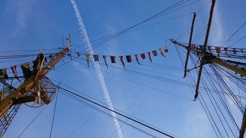 Low angle view of electricity pylon against blue sky