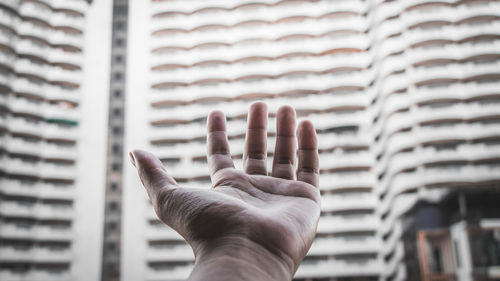 Cropped hand reaching buildings in city