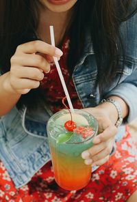 Midsection of woman having drink in glass