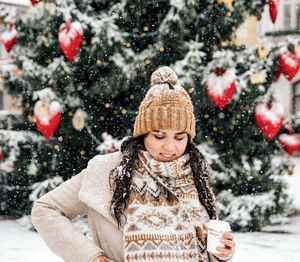 Portrait of a young woman drinking coffee from a paper coffee to go cup. winter, christmas, snowing.