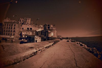 Buildings by sea against clear sky at night