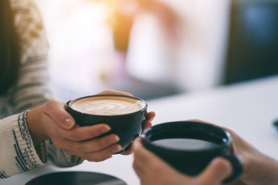 Midsection of woman holding coffee cup at cafe