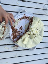 Cropped image of hand holding cake slice on table