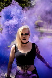 Portrait of young woman with make-up standing against smoke
