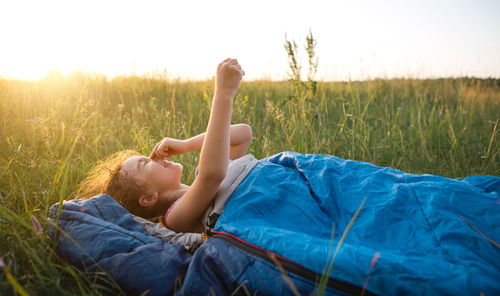 Girl lying amidst plants on sunny day