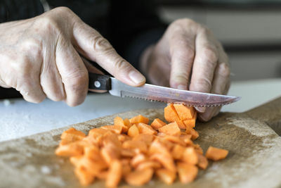 Midsection of man chopping carrots on cutting board