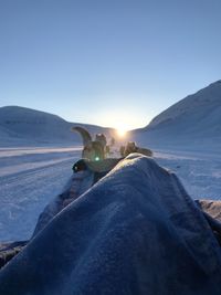 Low section of people on snowcapped mountain against clear sky