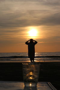 Silhouette man standing on beach during sunset