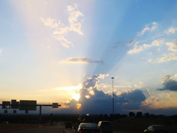 Cars on street against sky during sunset