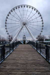 View of ferris wheel against cloudy sky