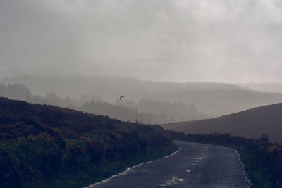 Road by mountains against sky